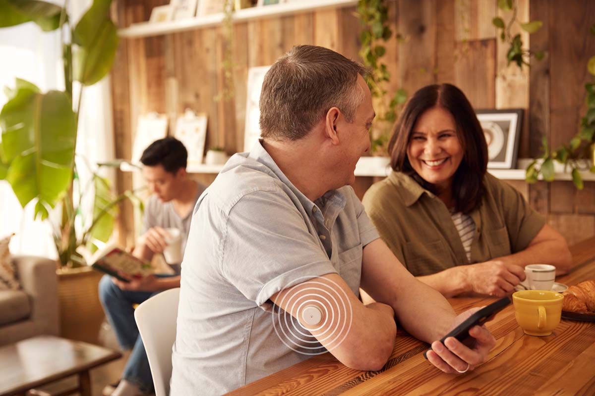 Couple out to dinner, one is casually looking at their phone to see their CGM readings