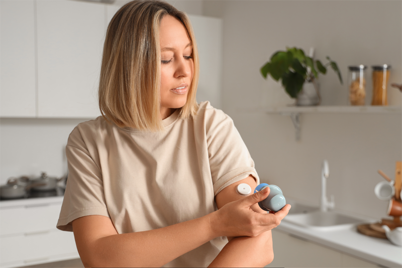 A woman applying a CGM onto their arm. 