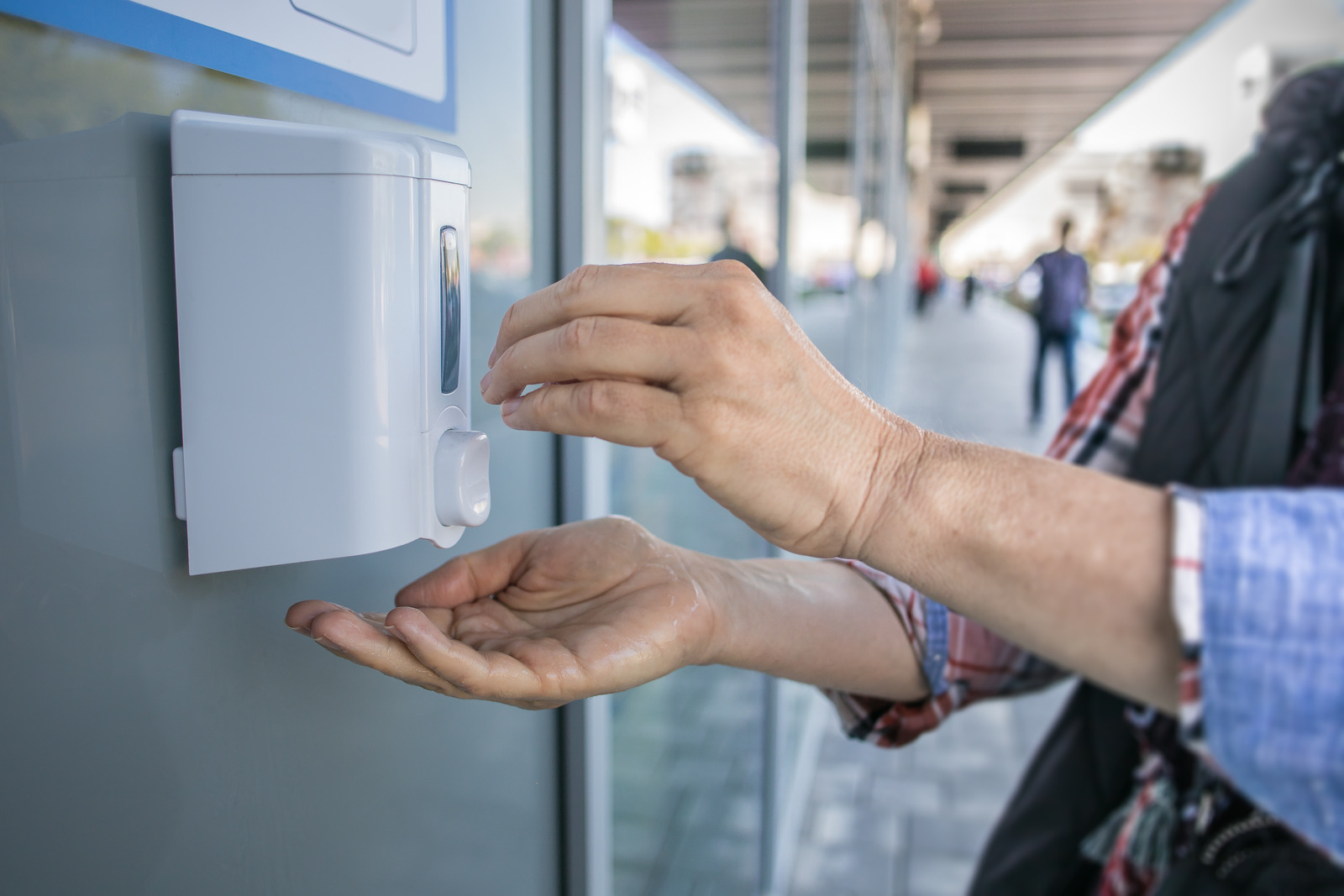 A woman using a hand sanitizer station  