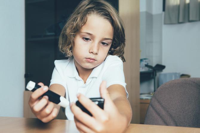 A child looking at blood sugar monitoring equipment. 